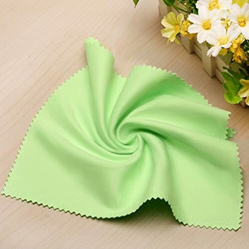 Green microfiber cleaning cloth on a table near flowers